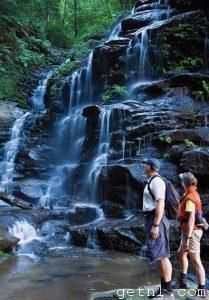 Bushwalkers admiring a cascading waterfall in the heart of the Blue Mountains, Australia
