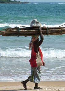A local woman carrying a heavy load in the traditional manner along the beach at Busua, Ghana