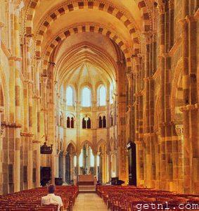 The Romanesque nave of the Basilica of Vézelay with sunlight spilling through the tall windows