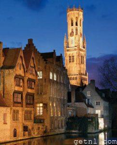 The canal at dusk, with the towering Belfry illuminated in the background, Bruges, Belgium